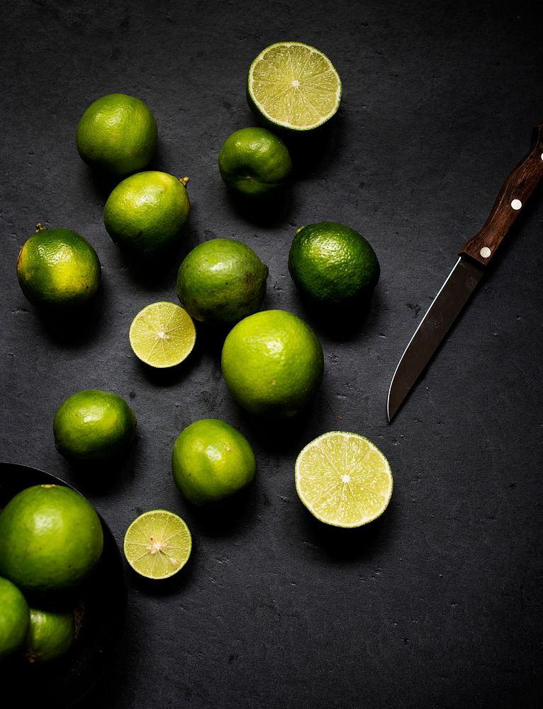 Limes with knife on black background