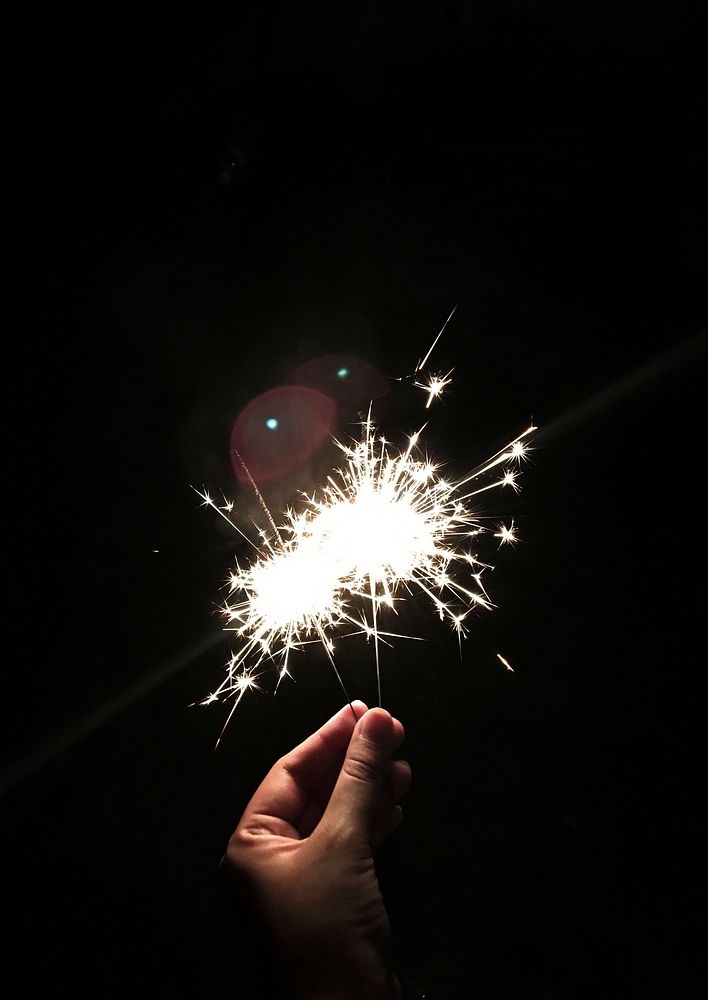 Closeup of hand holding sparkler with black background