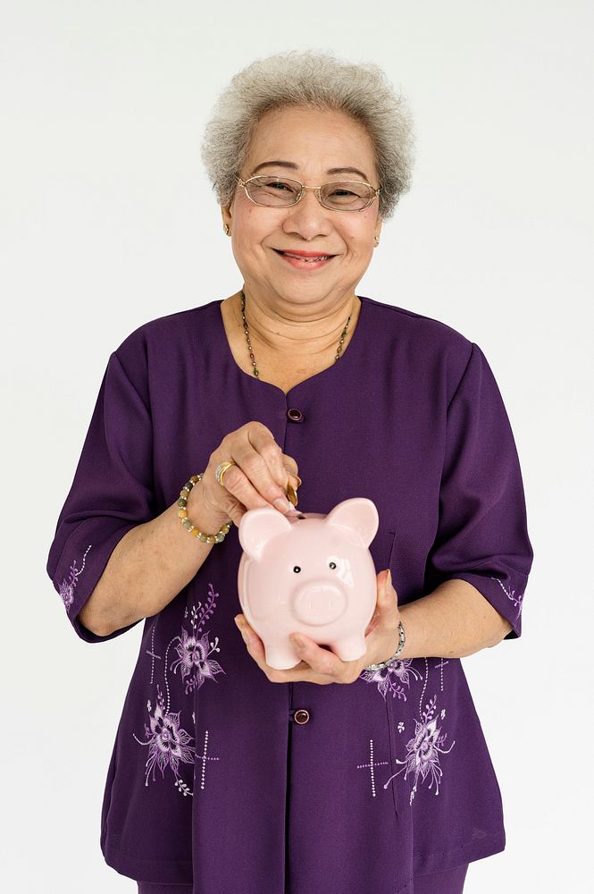 Studio portrait of a senior lady holding a piggy bank