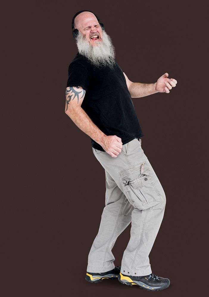 Studio portrait of a bearded man listening to music playing air guitar