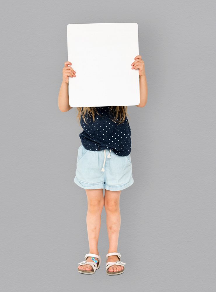 Little girl smiling and holding blank placard cover her face