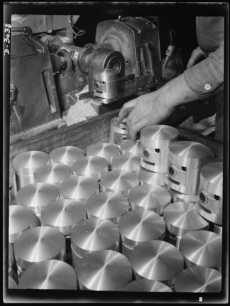 Aluminum casting. The reaming of pin holes in pistons. These bright cylinders are destined for use in the army's jeeps.…