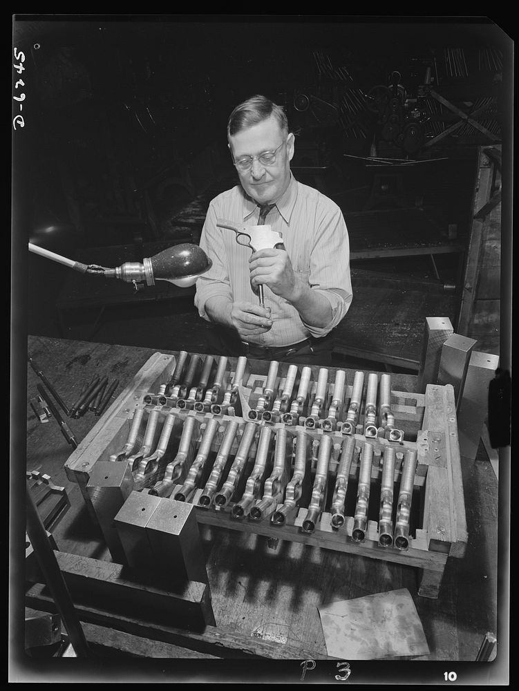 Production. 45-caliberautomatic pistols. William Watson gauges and inspects barrel drilling holes on .45-caliber automatic…