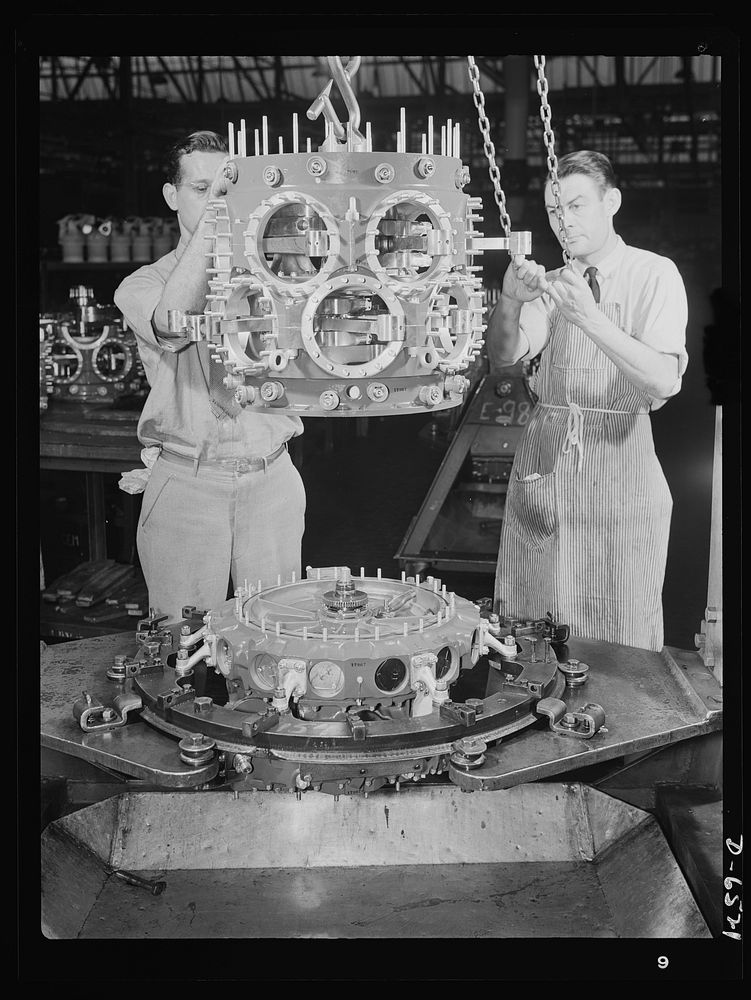 Production. Pratt and Whitney airplane engines. A power section assembly is lowered to blower case assembly as another Pratt…