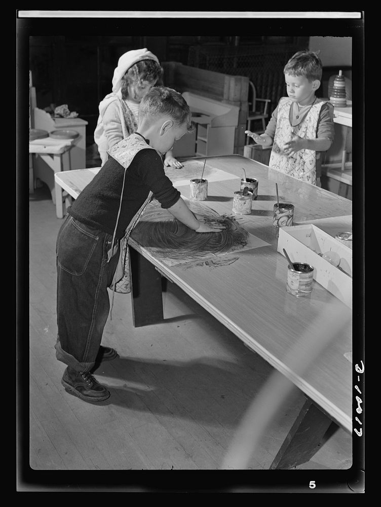 War workers' nursery. Finger painting is a healthy outlet for nursery school youngsters. With oilcloth aprons to protect…