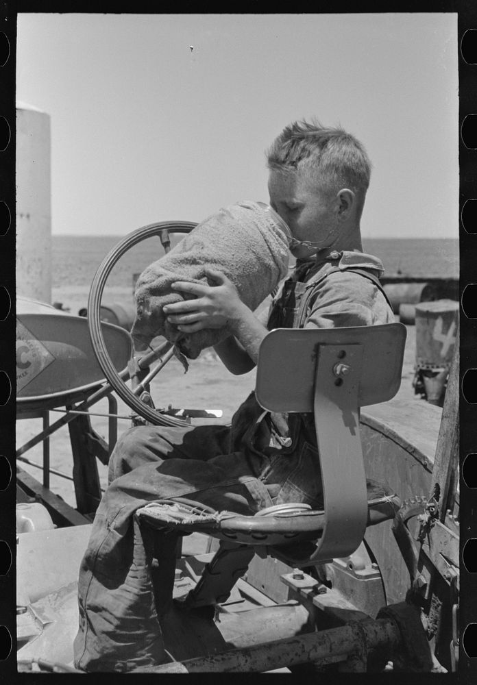 Son of day laborer on farm near Ralls, Texas. He is drinking from the jug which is carried on his father's tractor by…