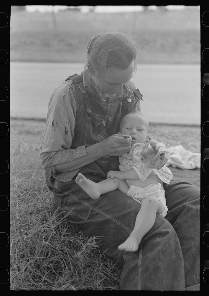 [Untitled photo, possibly related to: Migrant mother feeding her baby while the family was stopped by the roadside for…