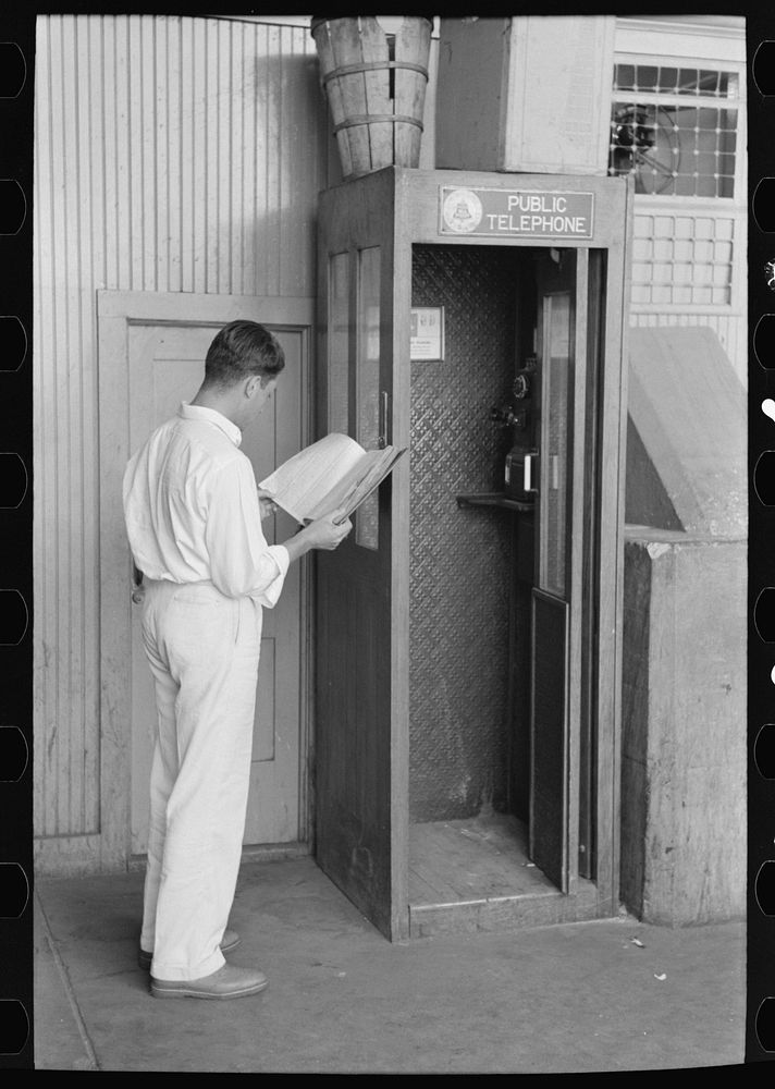 Man looking up telephone number. Streetcar terminal, Oklahoma City, Oklahoma by Russell Lee
