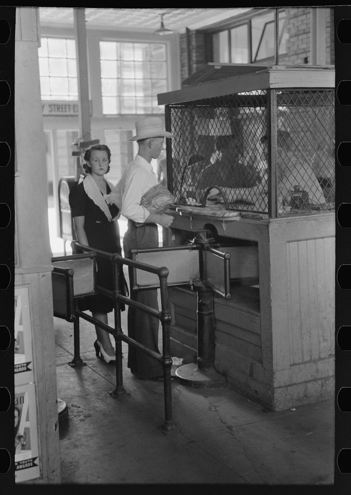 Young couple buying tickets at entrance turnstile. Streetcar terminal, Oklahoma City, Oklahoma by Russell Lee