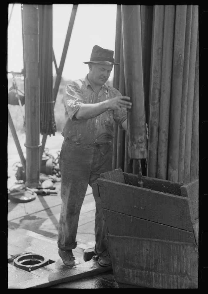 [Untitled photo, possibly related to: Roughneck guiding bailer into hole during bailing out operations, oil well near…