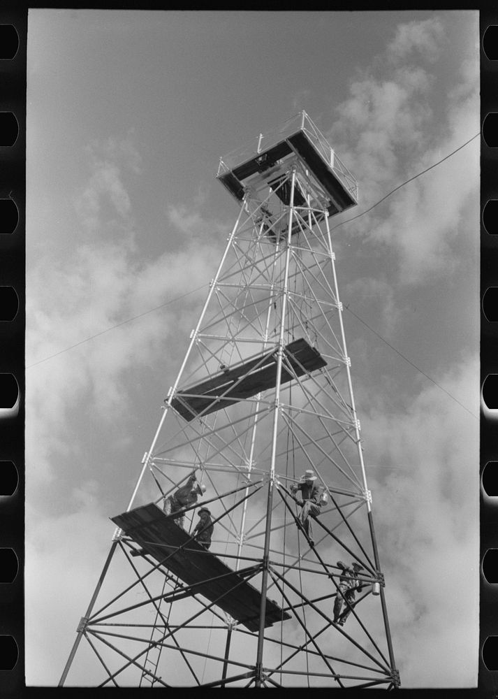 Painting a derrick, Seminole oil field, Oklahoma. Notice lack of safety belts. Painters say that safety devices slow them…