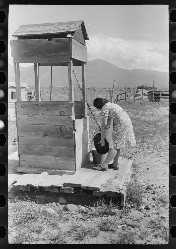 [Untitled photo, possibly related to: Daughter of Spanish-American farm family drawing water at the well, Taos County, New…