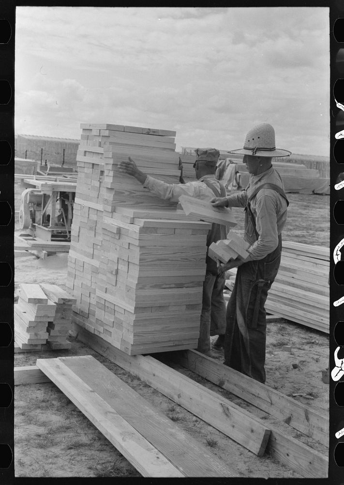 Piling precut blocks of wood at migrant camp under construction at Sinton, Texas by Russell Lee