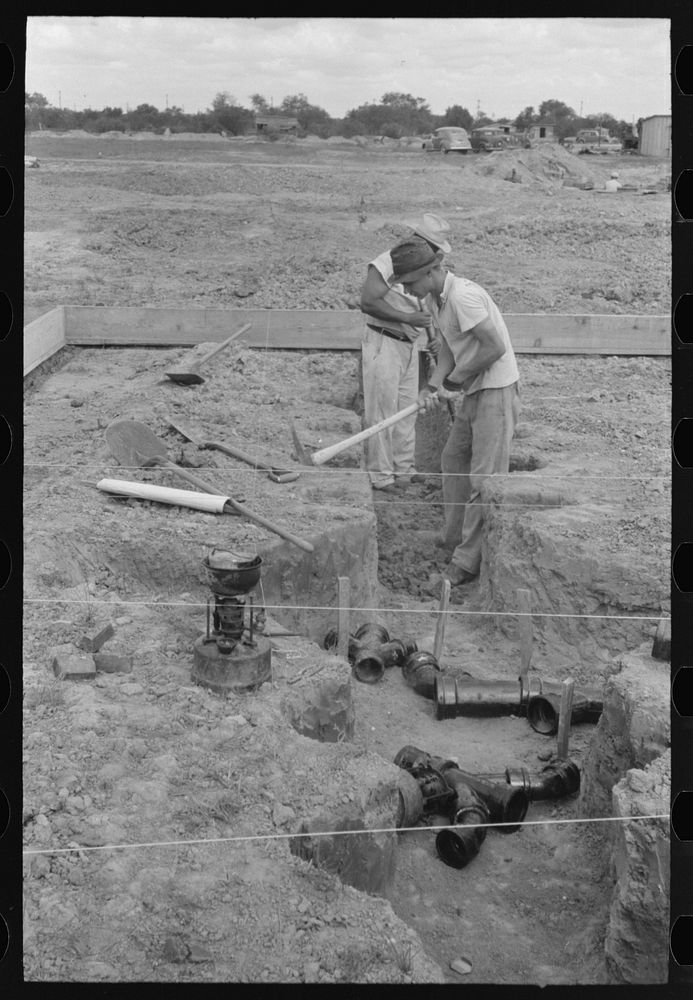 [Untitled photo, possibly related to: Soldering a joint of cast iron sewer pipe at migrant camp under construction at…