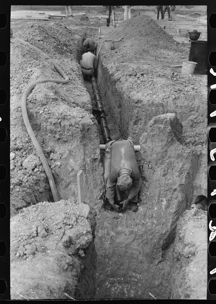 Laying sewer pipe in migrant camp in Sinton, Texas by Russell Lee