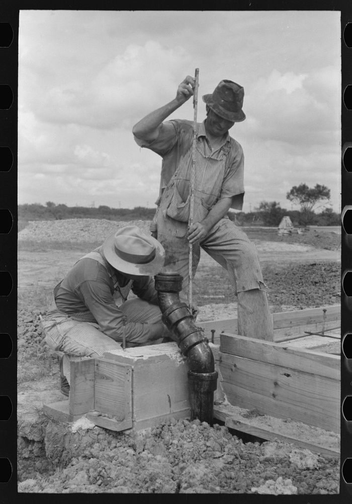 Workman checking measurements at migrant camp under construction at Sinton, Texas by Russell Lee