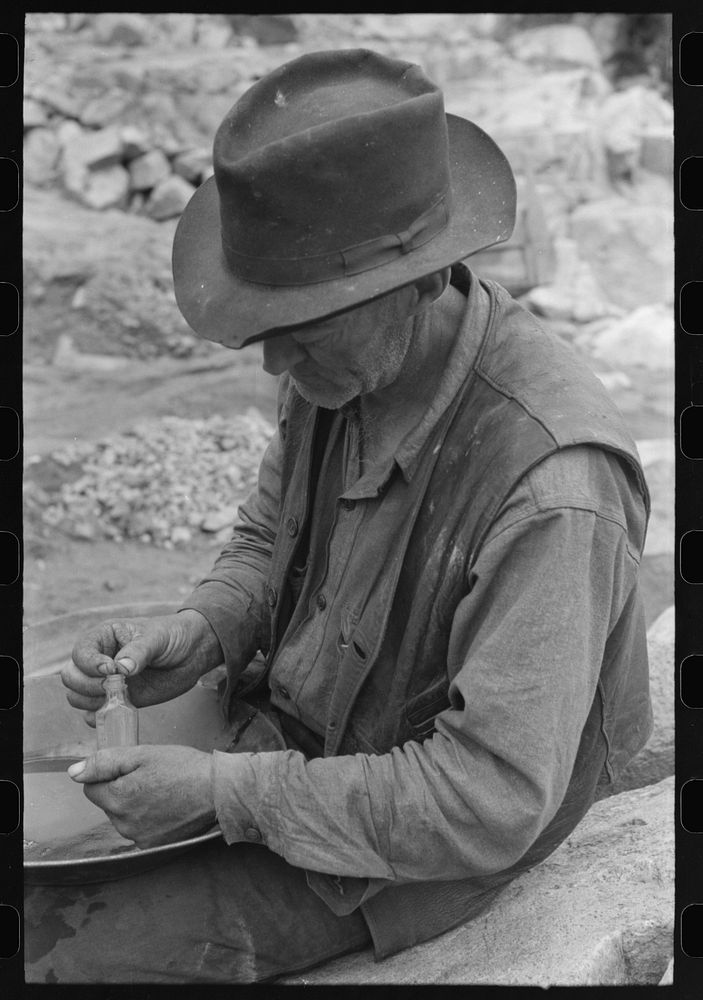 [Untitled photo, possibly related to: Gold prospector putting flakes of gold which he has recovered through wet washing and…