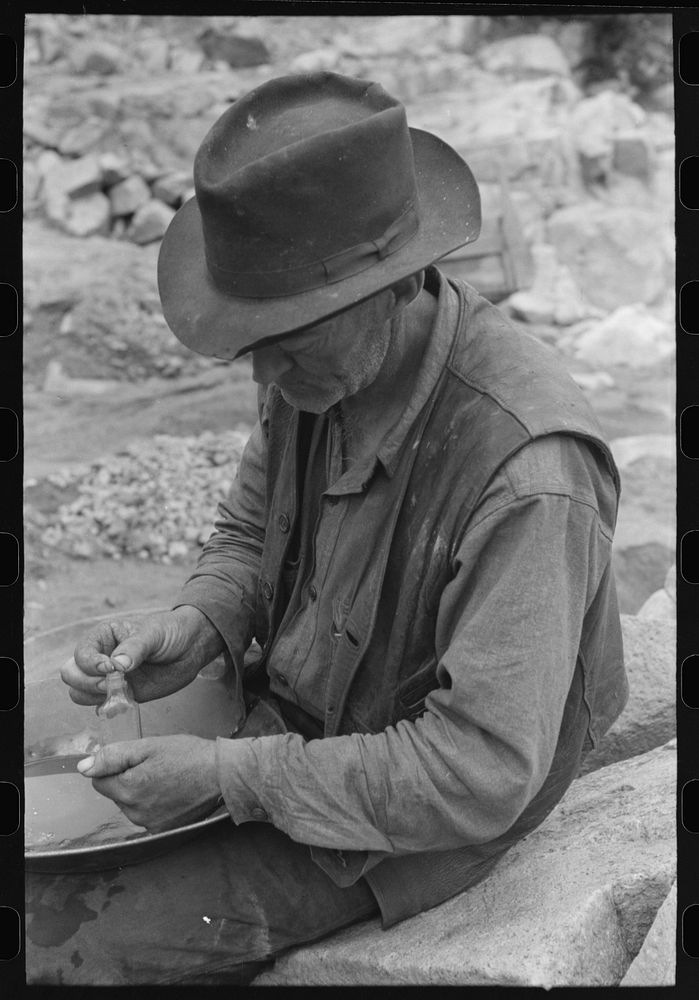 Gold prospector putting flakes of gold which he has recovered through wet washing and panning into bottle. Pinos Altos, New…