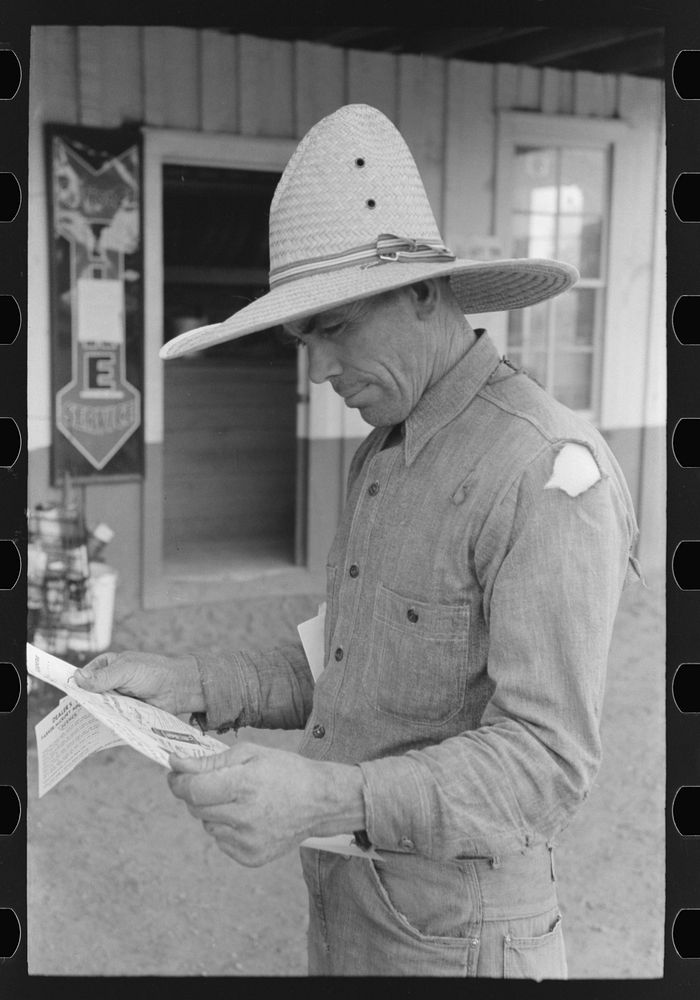 Mr. Leatherman studies some literature on electric fencing. Pie Town, New Mexico by Russell Lee