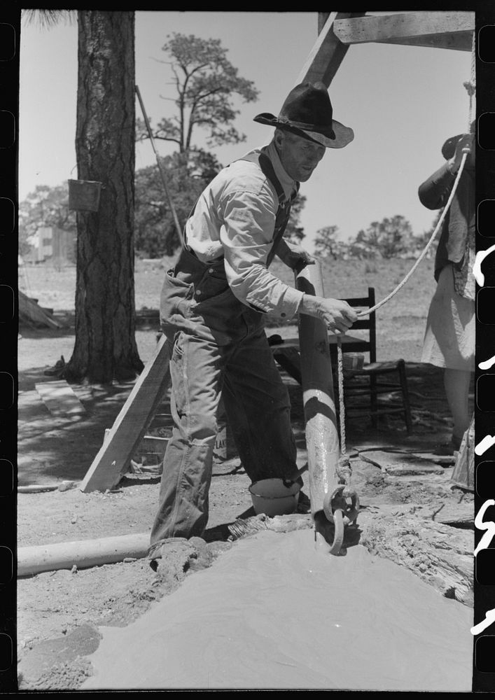 Farmer emptying slush from well which he is drilling with cable tools. Pie Town, New Mexico by Russell Lee