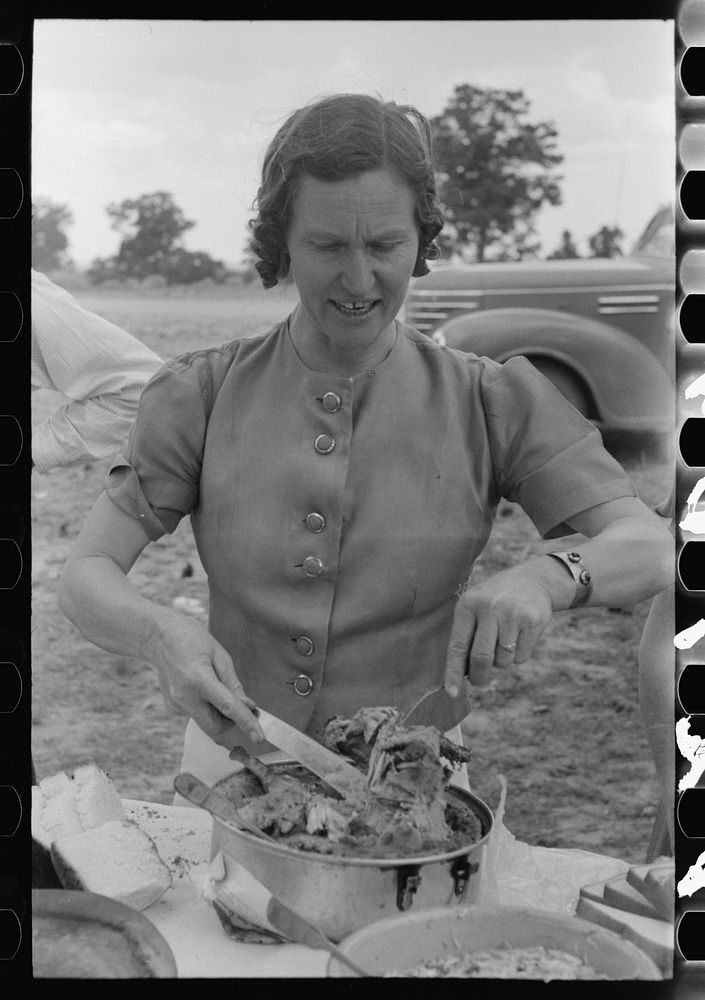 Mrs. Leatherman, homesteader from West Texas taking up chicken and dressing at dinner during the all day community sing. Pie…