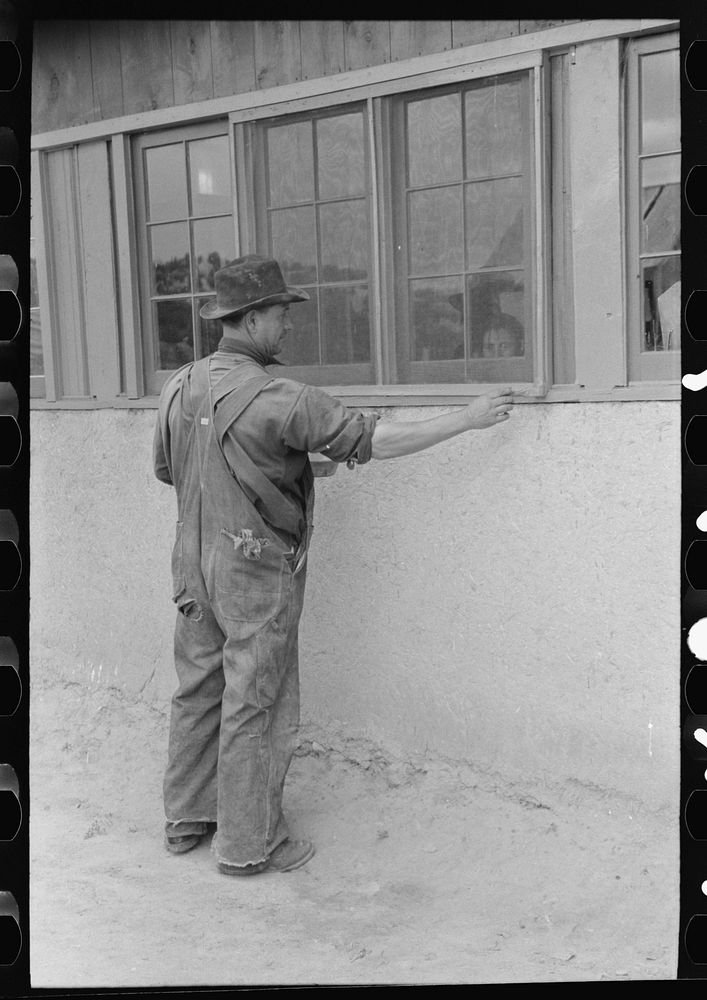 Spanish-American farmer painting window frames on his house. Spanish-American are proud of their houses. They are kept in…