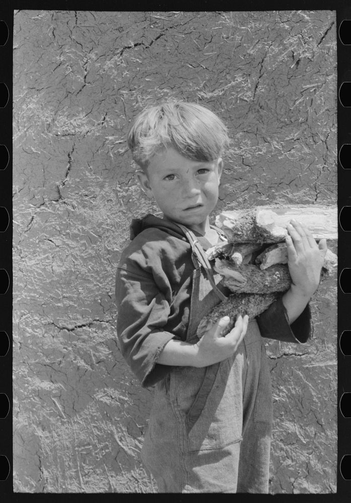 Spanish-American boy with an armful of wood. Chamisal, New Mexico by Russell Lee
