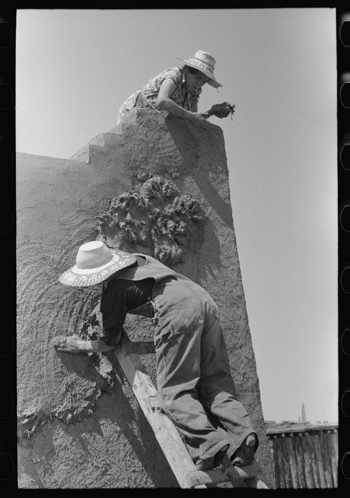 Spanish-American women plastering adobe house, Chamisal, New Mexico by Russell Lee