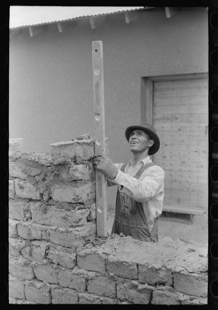 Using a level in constructing a window opening of an adobe house. Penasco, New Mexico by Russell Lee