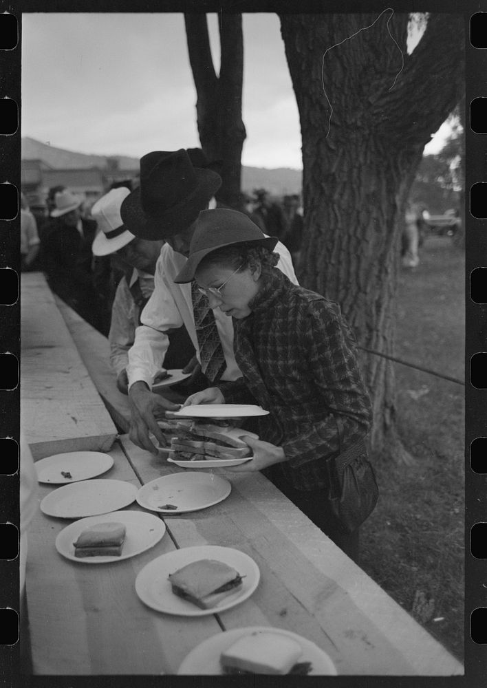 Covering a plate of barbecue sandwiches with another plate to protect the food from the rain, Labor Day at Ridgway, Colorado…