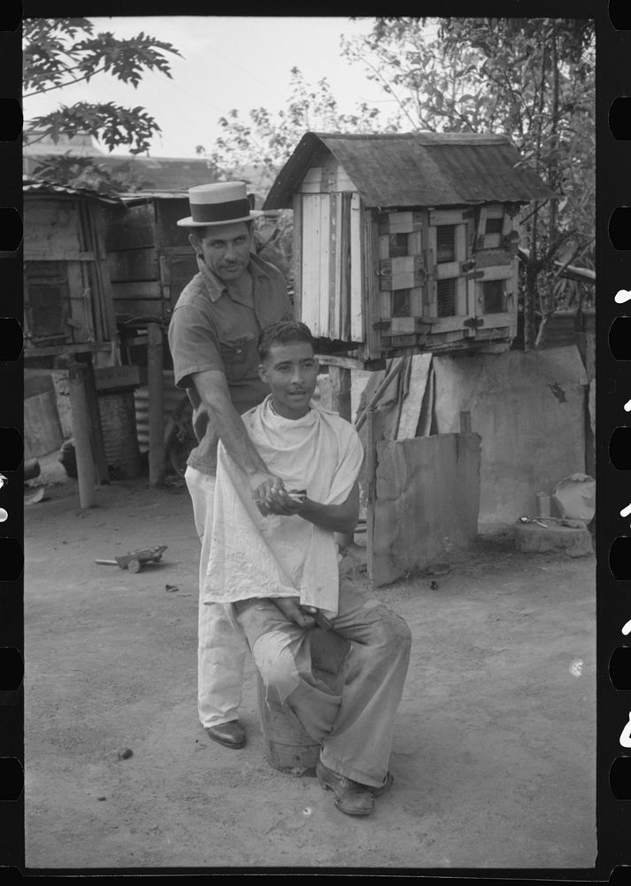 [Untitled photo, possibly related to: Yabucoa, Puerto Rico. Striker getting a haircut in the mill village near the sugar…