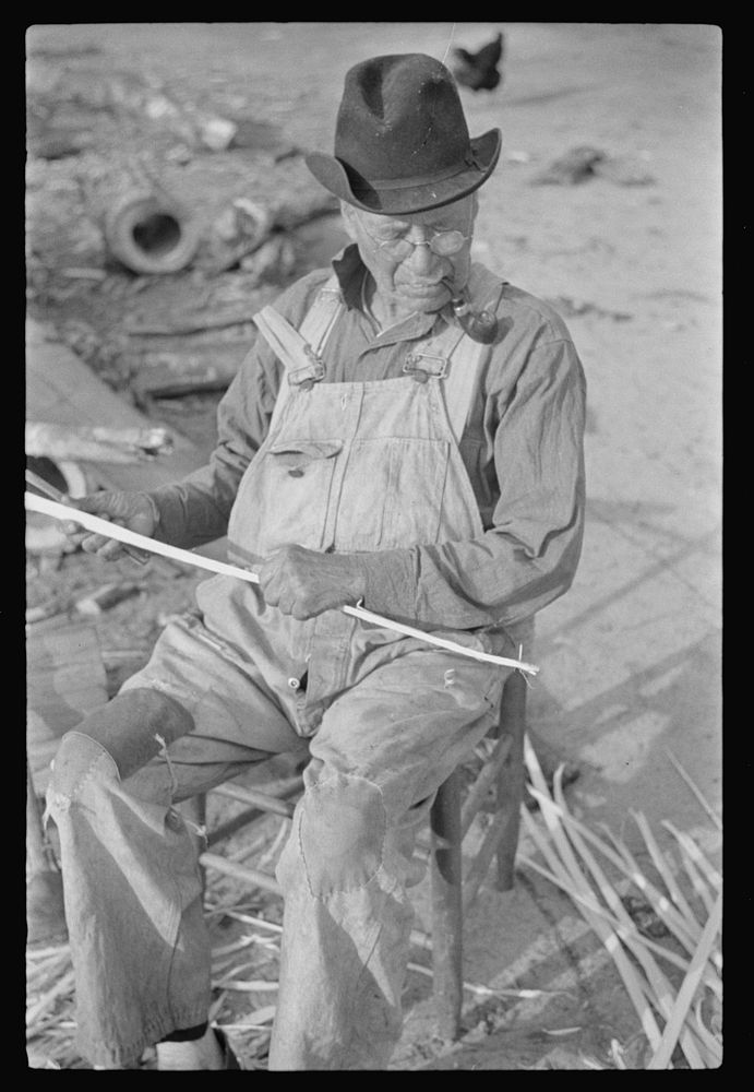 [Untitled photo, possibly related to: Man sitting near Pembroke Farms, making new chair seat. North Carolina] by Marion Post…