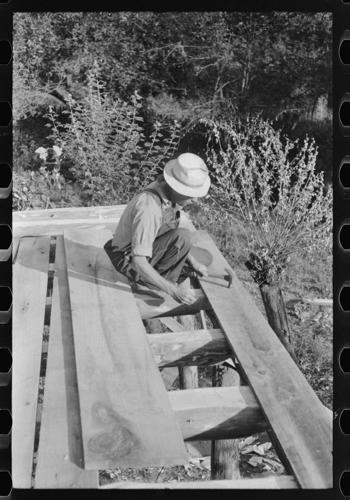Mountaineer laying the new floor in his neighbor's home near Jackson, Breathitt County, Kentucky. Sourced from the Library…