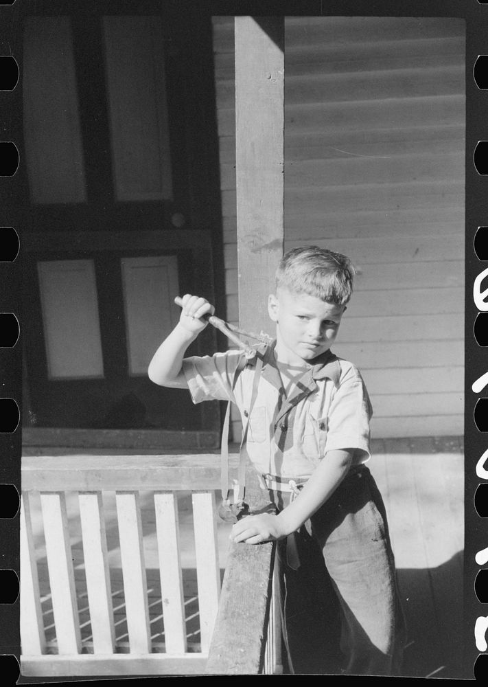 [Untitled photo, possibly related to: Mountain child shooting slingshot from porch of his home. Near Buckhorn, Kentucky].…
