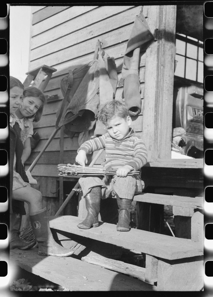[Untitled photo, possibly related to: Spanish muskrat trapper's son with stretched skins in his hands. In back of their camp…