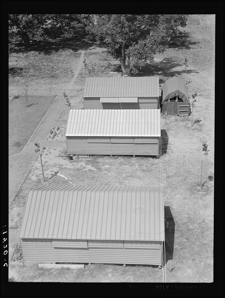 Farm Security Administration (FSA) camp for migratory agricultural workers. Farmersville, California. Shows prefabricated…
