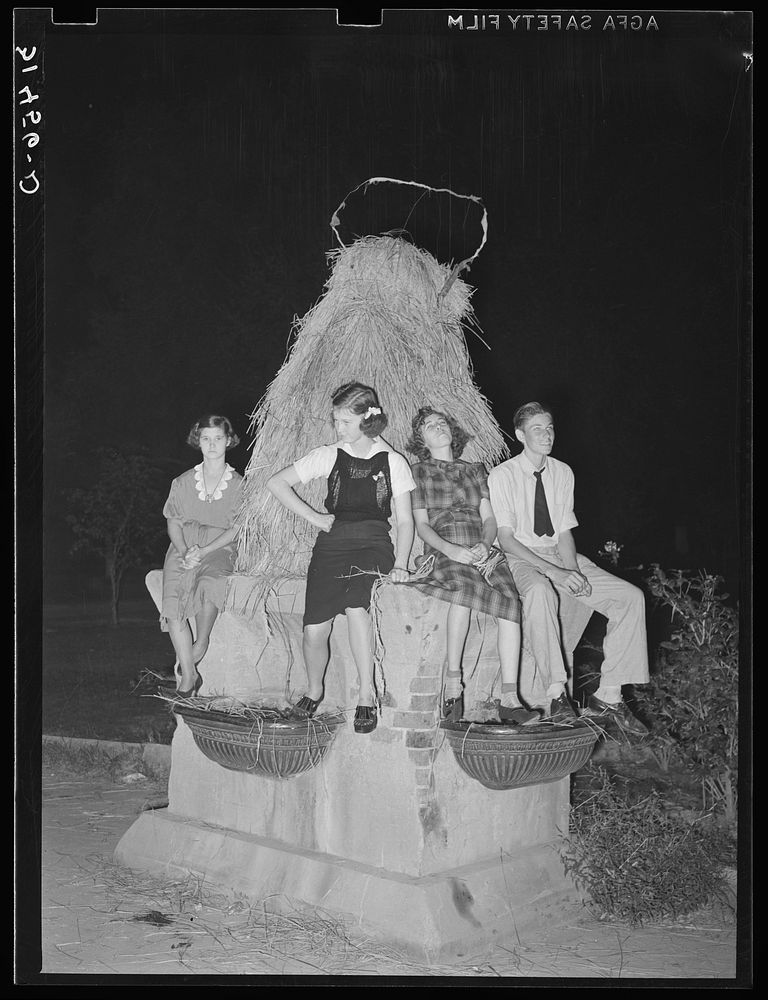 Sitting on decorated water trough watching the night parade at the National Rice Festival. Crowley, Louisiana by Russell Lee