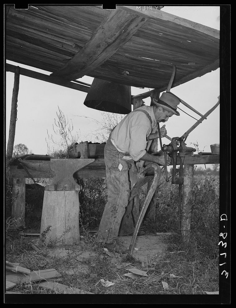 W.E. Smith, farmer near Morganza, Louisiana, doing smith work on plow in his improvised blacksmith shop by Russell Lee