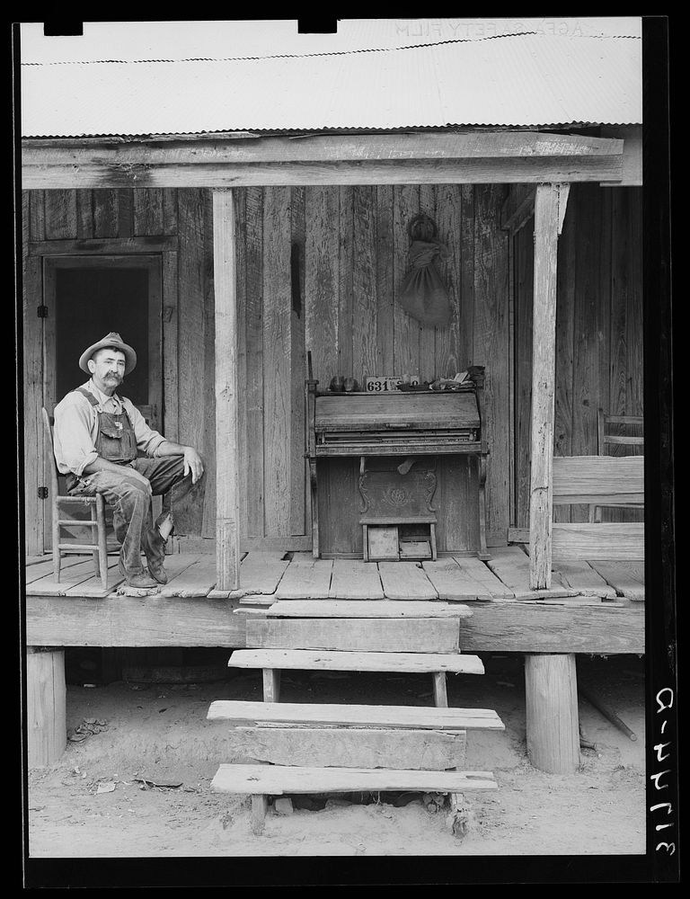 W.E. Smith, farmer near Morganza, Louisiana, sitting on the front porch of his home by Russell Lee