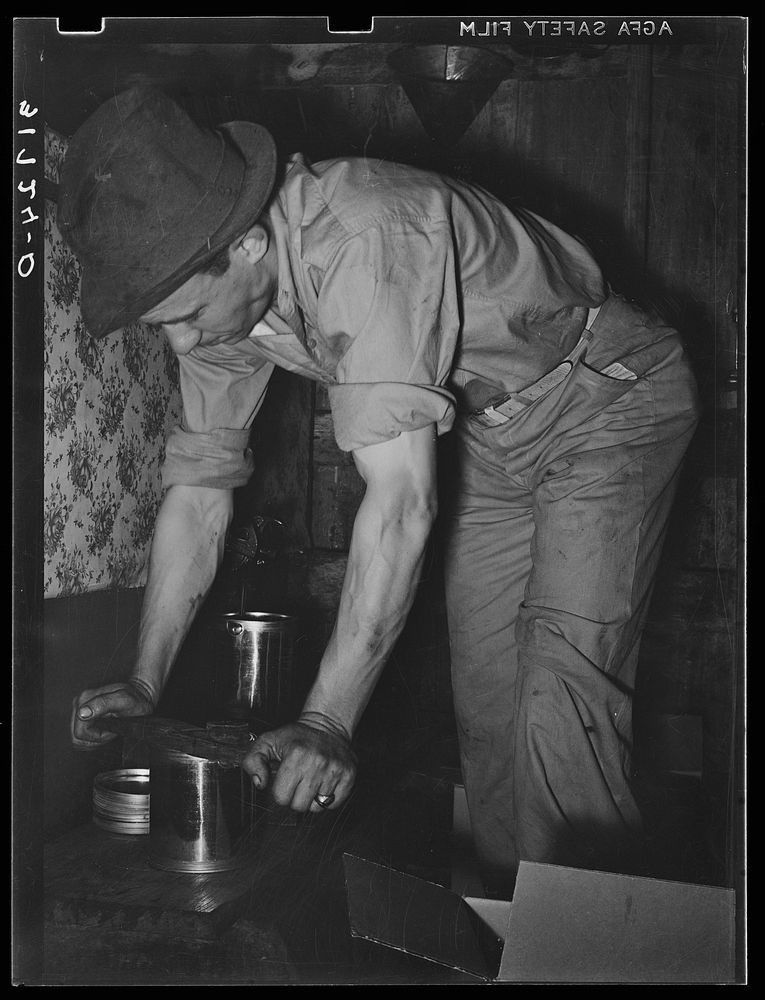 Pressing top onto tin can full of syrup. Syrup mill near New Iberia, Louisiana by Russell Lee