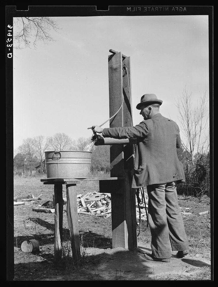 Ed Bagget, sharecropper, drawing water from well. Near Laurel, Mississippi by Russell Lee