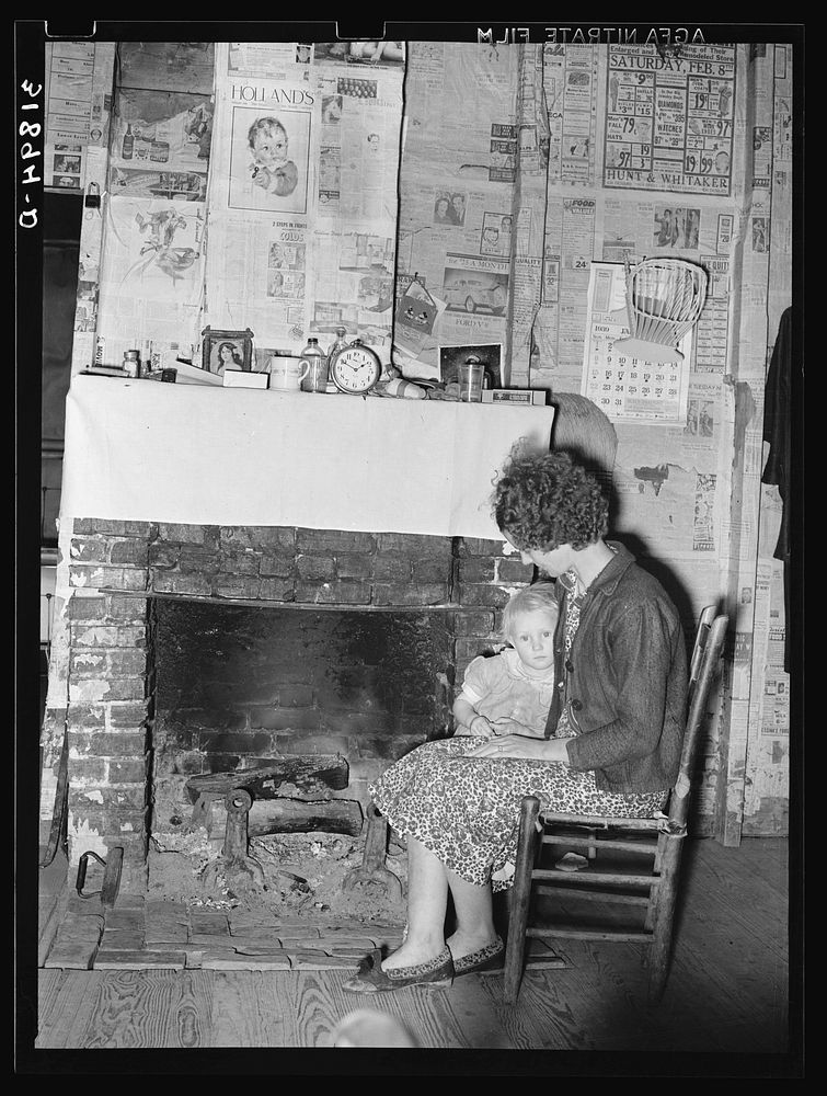 Wife and daughter of FSA (Farm Security Administration) client in front of fireplace of temporary home. Transylvania…