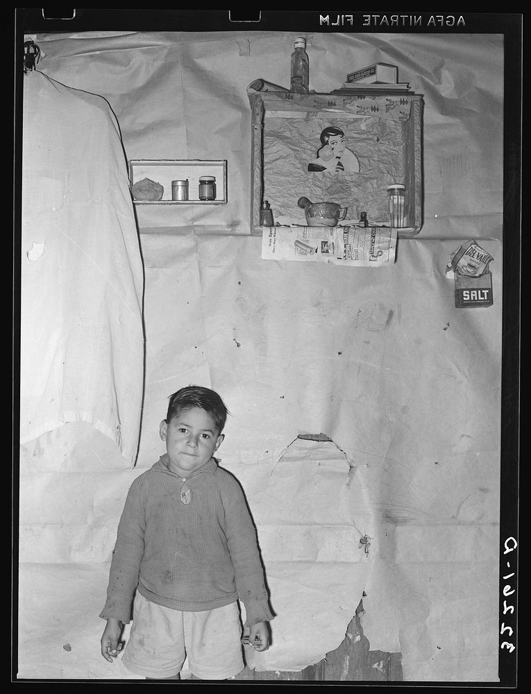 Mexican boy living in corral, Robstown, Texas. Notice the crude wall papering by Russell Lee