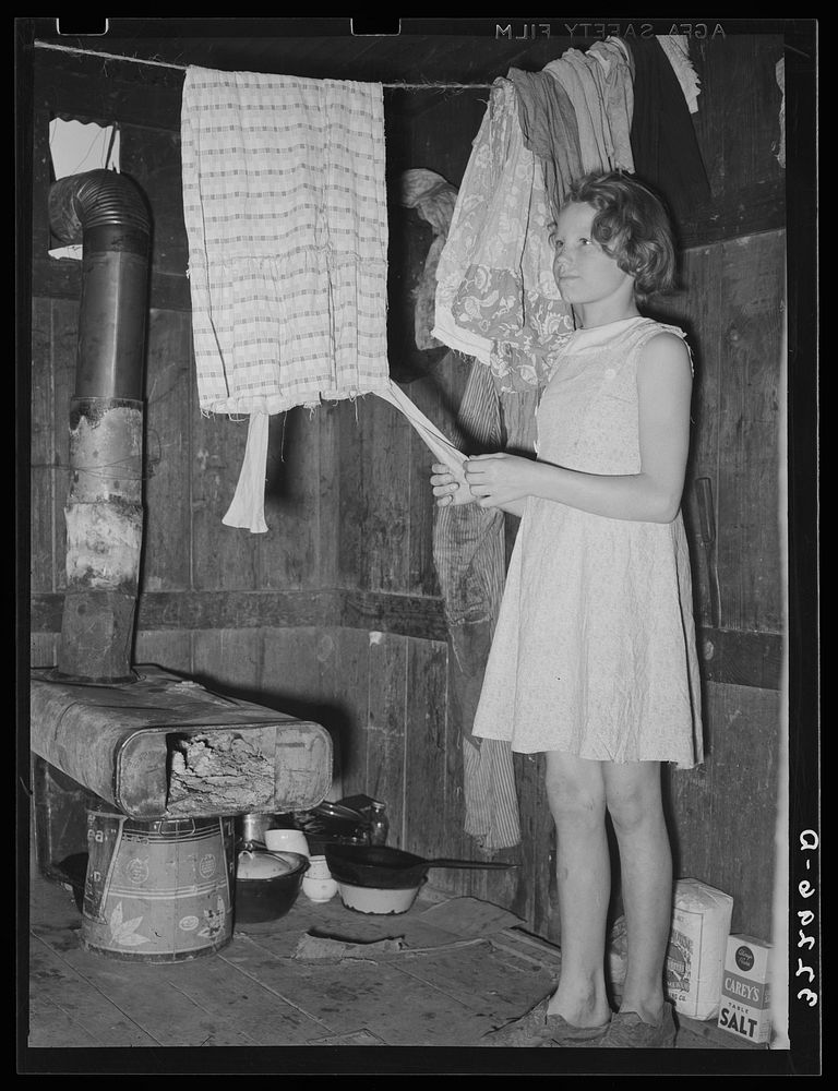 [Untitled photo, possibly related to: Mexican girl standing over pan of hot coal in which pail of water is heating.…