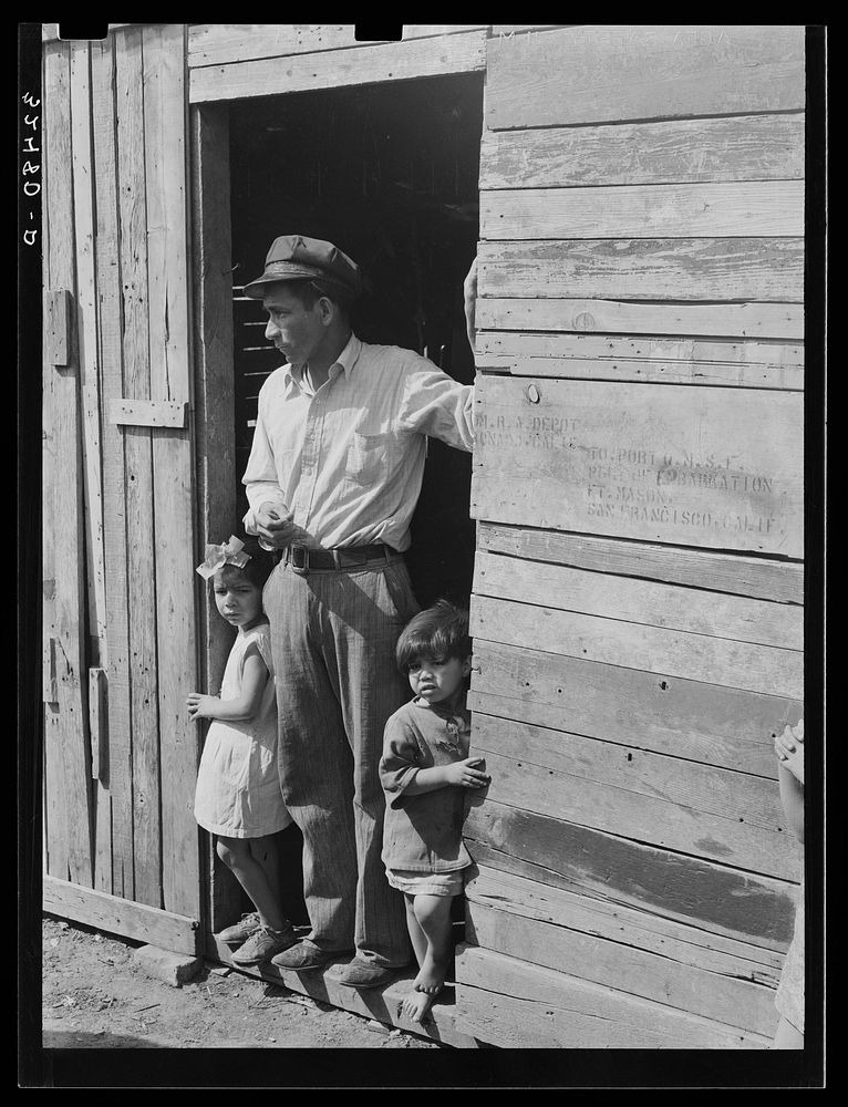 [Untitled photo, possibly related to: Mexican father and children in doorway of their home made of scrap lumber. San…