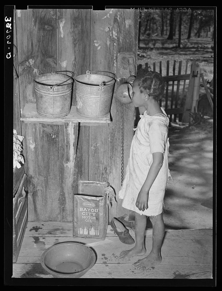 Daughter of  sharecropper drinking from hollow gourd. Near Marshall, Texas by Russell Lee