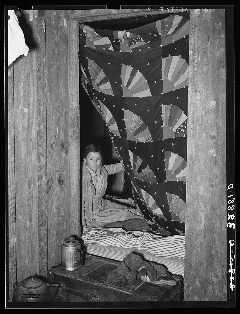 Quilt hung across doorway which separates living quarters of two families of white migrants. Berry pickers near Hammond…