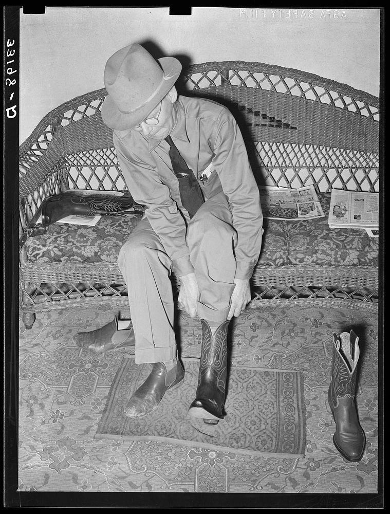 A customer trying on a pair of boots in bootmaking shop. Alpine, Texas by Russell Lee
