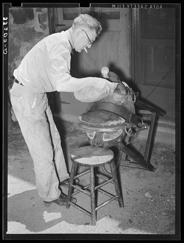 Applying pressure by means of sandbags to glued leather in saddle repairing shop. Alpine, Texas by Russell Lee
