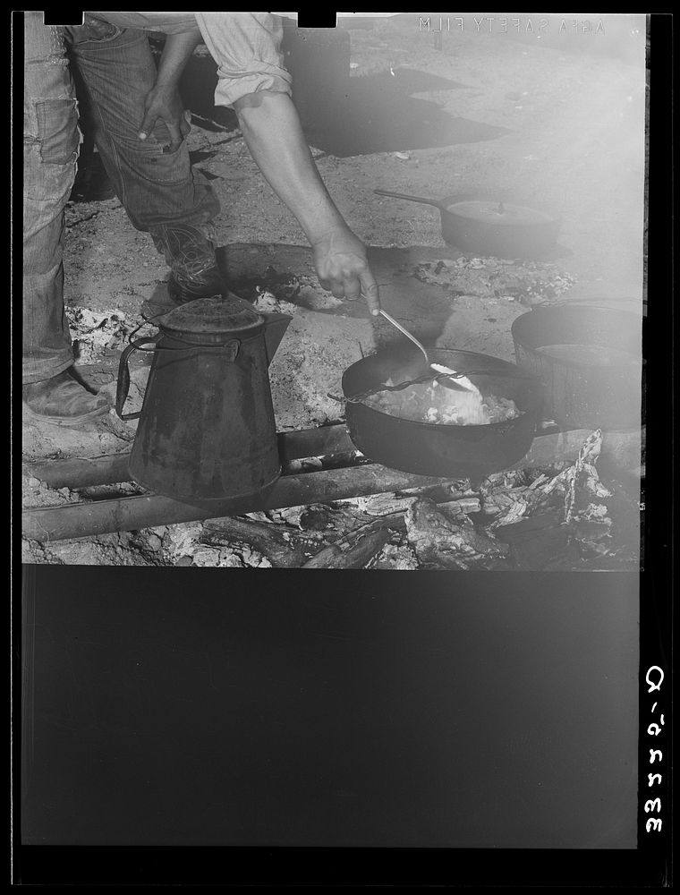 [Untitled photo, possibly related to: Camp cook at work with chuckwagon in background. Cattle ranch near Marfa, Texas] by…